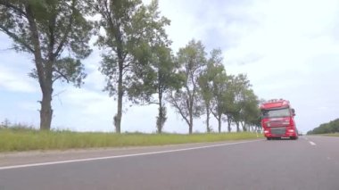 Kırmızı kamyon otoyol boyunca gidiyor. Bir grup kamyon otoyol boyunca gidiyor. Modern kamyonlar tanklarda sıvı kargo taşıyorlar