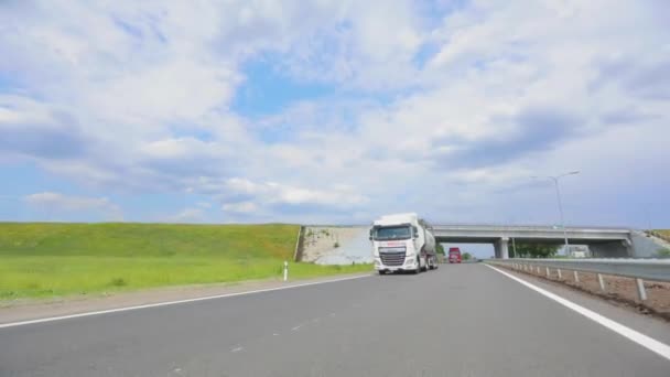 White truck driving along the highway. A truck with a tanker drives on the highway in sunny weather. A convoy of trucks drives along the highway — Stock Video