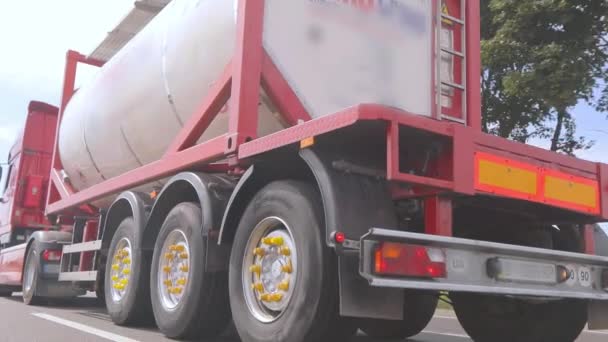 Vrachtwagens rijden langs de weg. Een vrachtwagen met een tankwagen rijdt langs de snelweg close-up. Vervoer van gevaarlijke goederen — Stockvideo