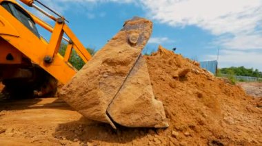 İnşaat alanında çalışma süreci. Traktör kovası yaklaş. Bir traktör inşaat alanında çukur kazıyor..