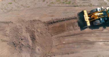 Havadan inşaat alanındaki modern traktör. Büyük sarı traktör. Profesyonel inşaat malzemeleri. İnşaat alanında çalışma süreci