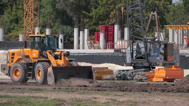 Żółty traktor na placu budowy. Proces pracy na placu budowy. Profesjonalny sprzęt budowlany. — Wideo stockowe