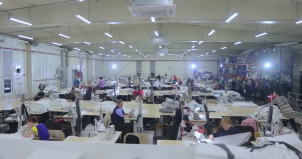 Een grote naaiproductie van tijdrondjes. Er zijn veel naaisters in de werkplaats. Kleding fabriek interieur. Vrouwen in de naaiindustrie — Stockvideo