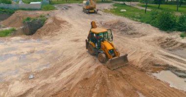 İnşaat alanında büyük sarı bir traktör. İnşaat alanında çalışma süreci. İnşaat alanında profesyonel ekipman.