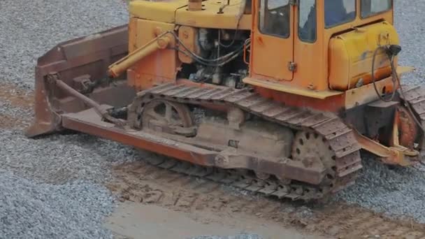 La excavadora amarilla trabaja en una obra de construcción. La excavadora nivela la capa de tierra. Buldózer amarillo en el sitio de construcción. Bulldozer en el sitio de construcción. Equipos de construcción pesados — Vídeo de stock