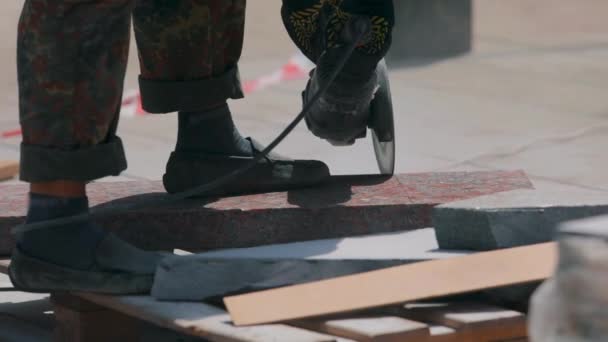 Un ouvrier coupe une dalle de granit avec une meuleuse. Processus de travail sur un chantier de construction. Travailler comme meuleuse sur un chantier — Video