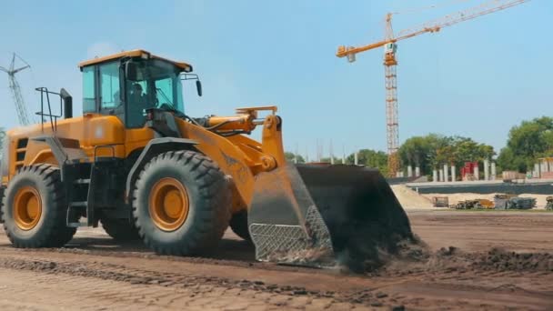 Sárga traktor egy építkezésen. Munkafolyamat egy építkezésen. Professzionális építőipari berendezések. — Stock videók