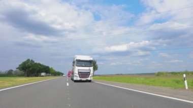 Tankerli bir kamyon güneşli havada otoyola çıkıyor. Otoyol boyunca giden beyaz bir kamyon. Bir kamyon konvoyu otoban boyunca gidiyor.