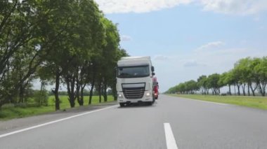 Otoyol boyunca giden beyaz bir kamyon. Tankerli bir kamyon güneşli havada otoyola çıkıyor. Bir kamyon konvoyu otoban boyunca gidiyor.