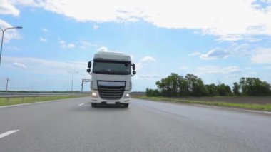 Tankerli bir kamyon güneşli havada otoyola çıkıyor. Bir kamyon konvoyu otoyol boyunca sürer. Otoyol boyunca giden beyaz bir kamyon..