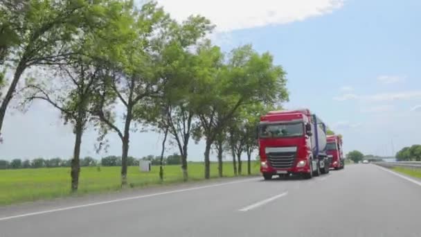 Caminhões modernos transportam carga líquida em tanques. O camião vermelho está a conduzir pela auto-estrada. Um grupo de caminhões está dirigindo ao longo da estrada. — Vídeo de Stock