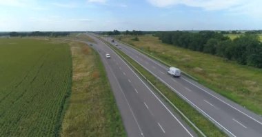 İnsansız hava aracının görüş alanında bir kamyon. Yeşil çimen manzaralı modern otoyolda kamyon turları
