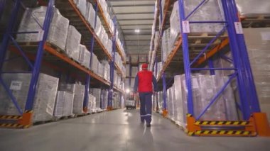 Depoya bakan bir adam var. Bir işçi modern bir depoda yürüyor. Depo çalışması