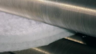 Sentetik kış sökücü üretimi. Sentetik kışlık konveyör hattında, yakın plan. Dokumasız malzeme üretimi için bir fabrika. Syntepon üretim süreci