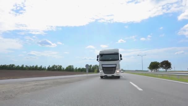 Biała ciężarówka jadąca autostradą. Nowoczesna ciężarówka jedzie wzdłuż autostrady. Transport towarów. Usługi logistyczne. Ciężarówka cysterna jadąca wzdłuż autostrady — Wideo stockowe