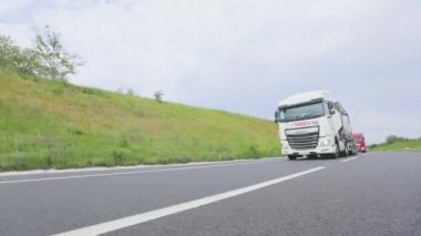 Tankerli bir kamyon güneşli havada otoyola çıkıyor. Bir kamyon konvoyu otoyol boyunca sürer. Otoyol boyunca giden beyaz bir kamyon..