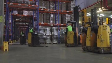 Fabrikanın deposunda özel ekipman var. Depoyu turlayan bir sürü forklift var. Modern yükleyiciler büyük bir depoda.