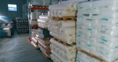 Spunbond fabrikanın deposunda rulo yapıyor. Fabrikadaki hammadde deposu. Üretim için bir sürü hammadde torbası..
