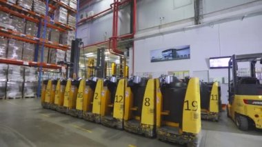 Fabrikanın deposunda özel ekipman var. Depoyu turlayan bir sürü forklift var. Modern yükleyiciler büyük bir depoda.
