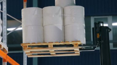 Forklift malları ambarın rafına koyuyor. Forklift, el değmemiş olanları fabrika deposunun rafına koyuyor. Dokumasız fabrikadaki depo..