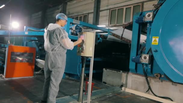 Ein Mann am Armaturenbrett einer Maschine in einer Fabrik. Ein Arbeiter am Bedienpult eines modernen Förderers. Arbeiter in einer modernen Fabrik. — Stockvideo