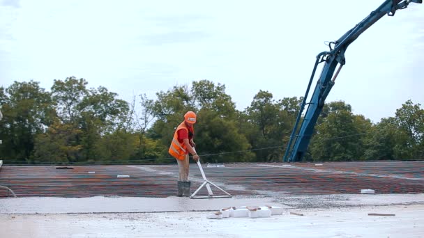 Lavorare con calcestruzzo in un cantiere. Un lavoratore livella uno strato di calcestruzzo in una struttura di cemento armato. Creazione di moduli — Video Stock