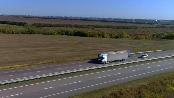 Вантажівка їде по шосе в сонячну погоду. Вантажівка їде по сучасній дорозі. Вантажівка на колії — стокове відео