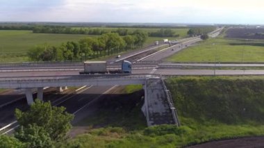Arabalar otoban boyunca gidiyor, manzarası çok güzel. Trafik kavşağı üst görünümü değiştir. Bir yol kavşağının üzerinden uçuyorlar. Arabalar şehrin dışındaki otoyol boyunca ilerliyorlar.