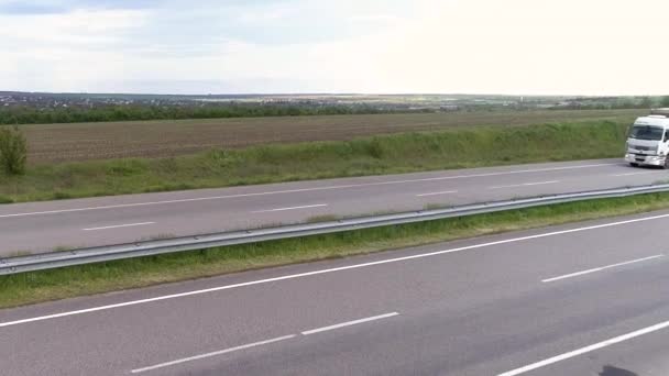 Ciężarówka na autostradzie widok z drona. Przejażdżki ciężarówką po nowoczesnej autostradzie wokół zielonej trawy widok z góry. Transport towarowy. Logistyka — Wideo stockowe