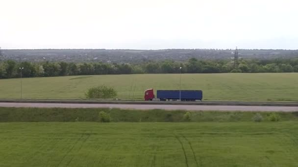 Ciężarówka jedzie autostradą. Ciężarówka jedzie wzdłuż drogi wśród zielonych pól. — Wideo stockowe