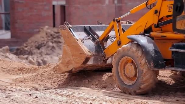 Der Traktor arbeitet auf einer Baustelle. Arbeitsprozess auf einer Baustelle. Schaufel eines Traktors aus nächster Nähe — Stockvideo