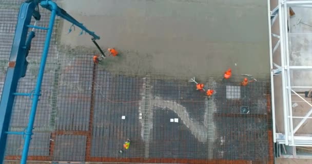 Byggarbetsplats från luften. Arbetarna häller betong över golvet i byggnaden. Byggarbetsplatsens vy från drönaren. Skapande av formarbeten — Stockvideo