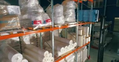 Dokumasız fabrikasındaki depo. Kumaşsız kumaş deposuna uçuş. Sentetik kış sarmalı büyük modern bir depo.