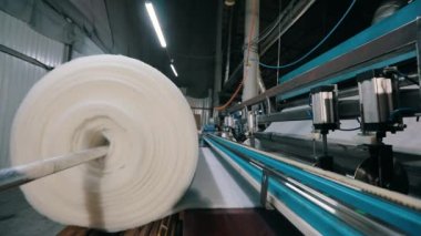 Büyük bir rulo sentetik kış sökücü. Syntepon üretim süreci. Endüstriyel iç.