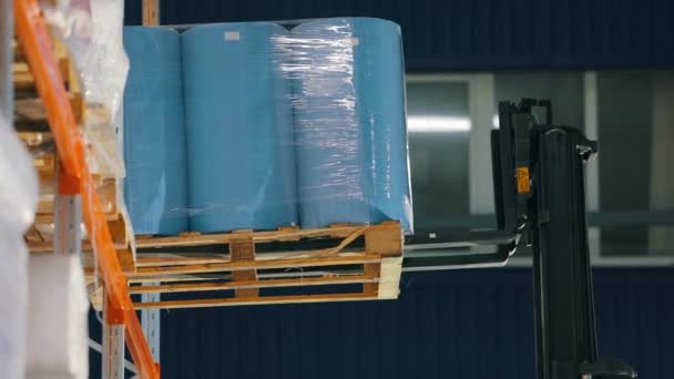 Vysokozdvižný vozík položí zboží na polici skladiště. Vysokozdvižný vozík dává netkané textilie na poličku továrního skladu. Skladiště v továrně netkaných textilií. — Stock video
