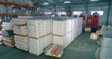 Spunbond fabrikanın deposunda rulo yapıyor. Fabrikadaki hammadde deposu. Üretim için bir sürü hammadde torbası..