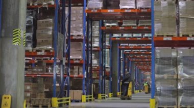 Fabrikanın deposunda özel ekipman var. Depoyu turlayan bir sürü forklift var. Modern yükleyiciler büyük bir depoda.