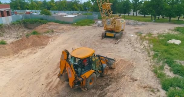 Traktor kuning besar di lokasi konstruksi. Proses kerja di lokasi konstruksi. Peralatan profesional di lokasi konstruksi — Stok Video