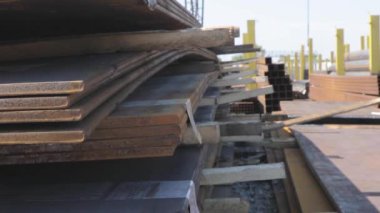 Açık gökyüzünün altındaki metal bir skala üzerindeki metal levhalar, iyi hava, arka planda kanatlı vinç olan metal levhalar, metal ürünler deposu, metal ürünler.