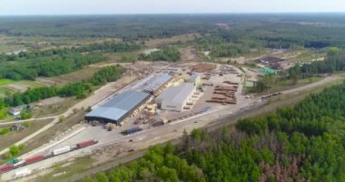 Büyük, modern bir kereste fabrikasının üzerinde uçan tren, tepeden kereste fabrikası manzarasının yanında duruyor. Modern marangoz fabrikası hava manzarası