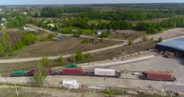 Yük treni, marangoz fabrikasının hava manzaralı bölgesinde yavaşça ilerliyor. Modern kereste fabrikası hava manzarası, büyük modern kereste fabrikası