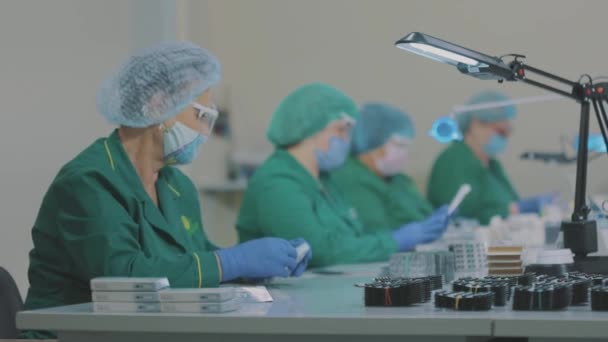 Flux de travail dans une usine pharmaceutique. Les ouvriers d'usine emballent des pilules. Travailleurs masqués. — Video