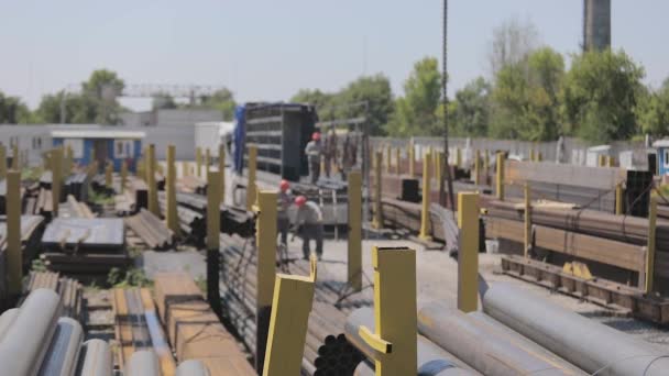 The working process in a warehouse with a metal. Workers unload a metal in a truck standing under a gantry crane, workers on a ramp. Loading a truck with a gantry crane — Stock Video