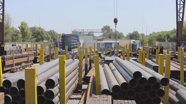 O processo de trabalho em um armazém com um metal. Os funcionários descarregam um metal em um caminhão que está abaixo de um guindaste de pórtico, funcionários em uma rampa. Carregando um caminhão com um guindaste pórtico — Vídeo de Stock