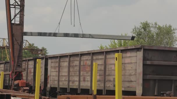 Carga de un tubo de perfil por una grúa pórtico en un vagón de carga, carga metal en un almacén, una grúa pórtico grande — Vídeos de Stock
