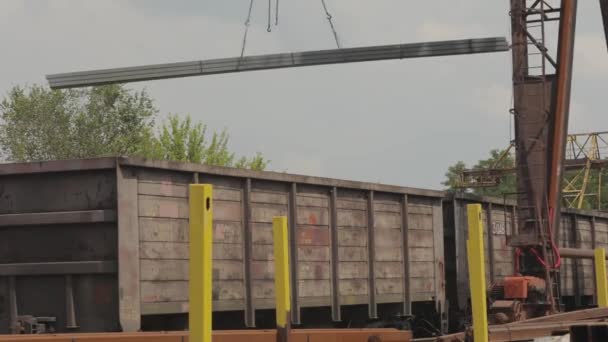 Verladung eines Profilrohres durch einen Portalkran in einen Güterwaggon, Verladung von Metall in eine Lagerhalle, ein großer Portalkran — Stockvideo
