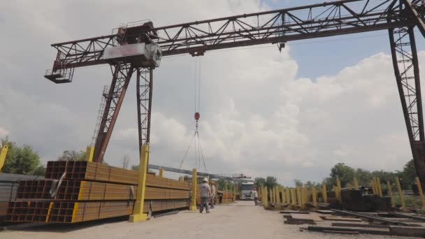 A gantry crane loads metal into a truck, loads metal in a warehouse, a large gantry crane, people work in a metal warehouse — Stock Video