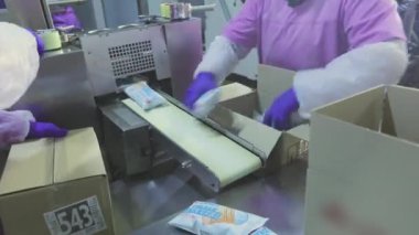 Konveyör karton kutulara gönderildikten sonra dondurma. Fabrika iş akışı. İşçiler kutulara dondurma koyarlar..