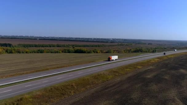 貨物トラックが高速道路を走っている。ドローンからの眺め。馬車は畑の間のカーブした道を走っている。 — ストック動画