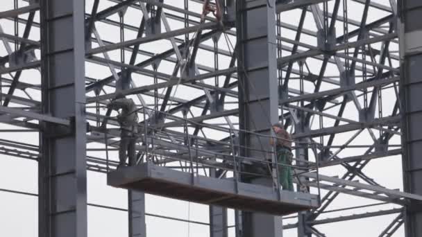 Werknemers schilderen metalen constructies. Bouwwerkzaamheden. Industriële buitenkant. Bouwers schilderen de metalen structuur van het gebouw vanaf een verpulveraar — Stockvideo